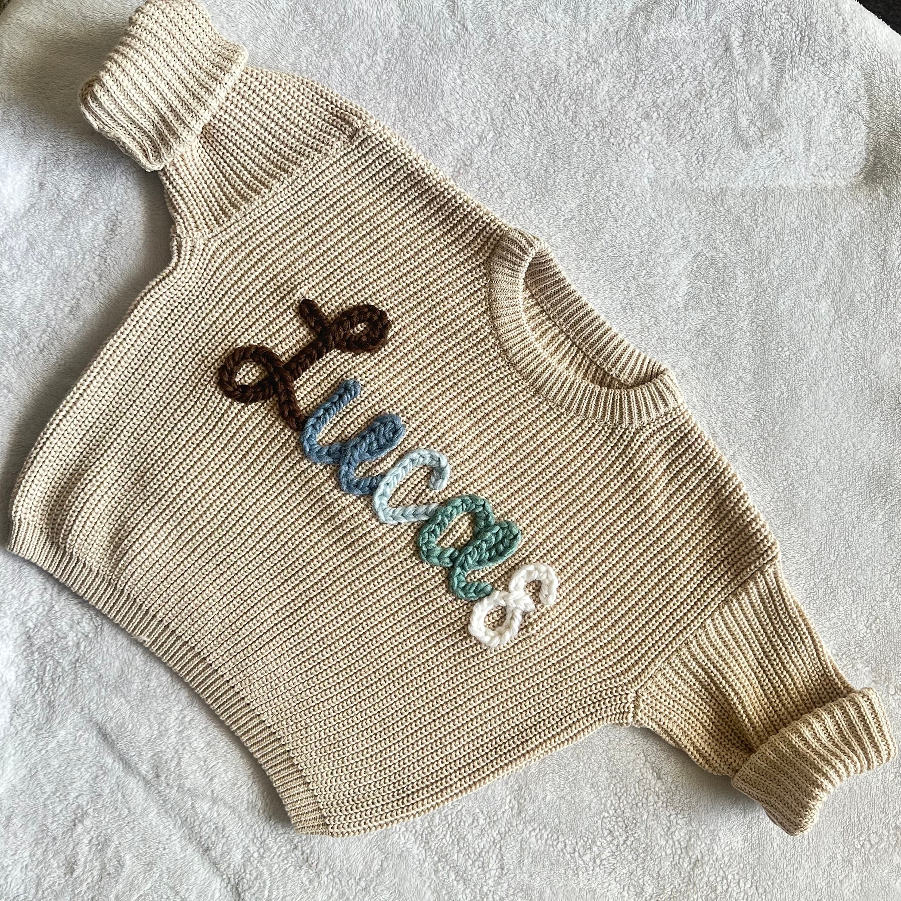 Cream sweater stitched with the name Lucas in brown and blue
